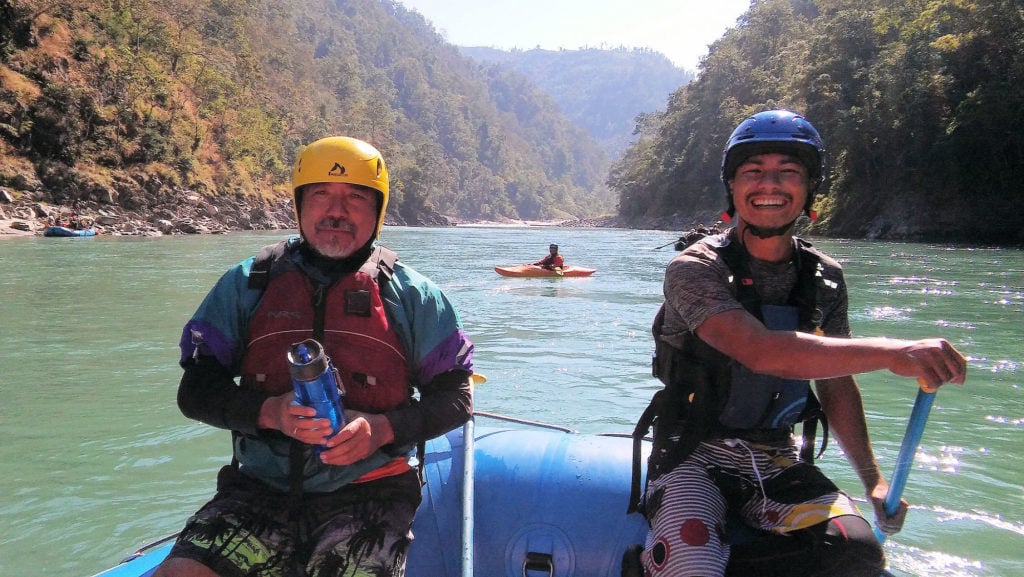 Two men posing on a raft in the river. 