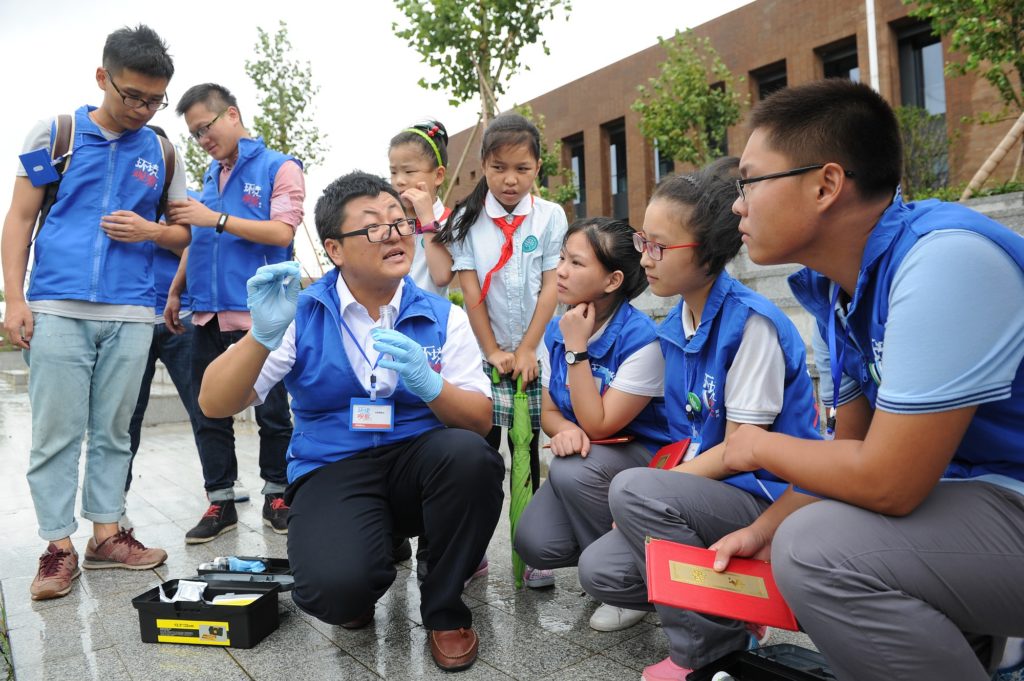 Hao Xin demonstrates water-quality testing to student volunteers at YinZhou Middle School. 
