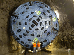 City workers stand in front of the massive boring machine used to cut through the granite 