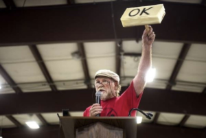 El opositor al GNL en Oregon sostiene un sello de goma hecho en casa durante la audiencia de la FERC en 2016.