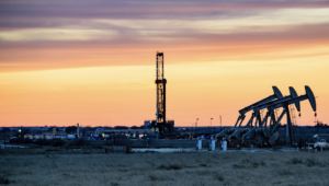 A gas drilling rig for fracking with a sunset in the background.