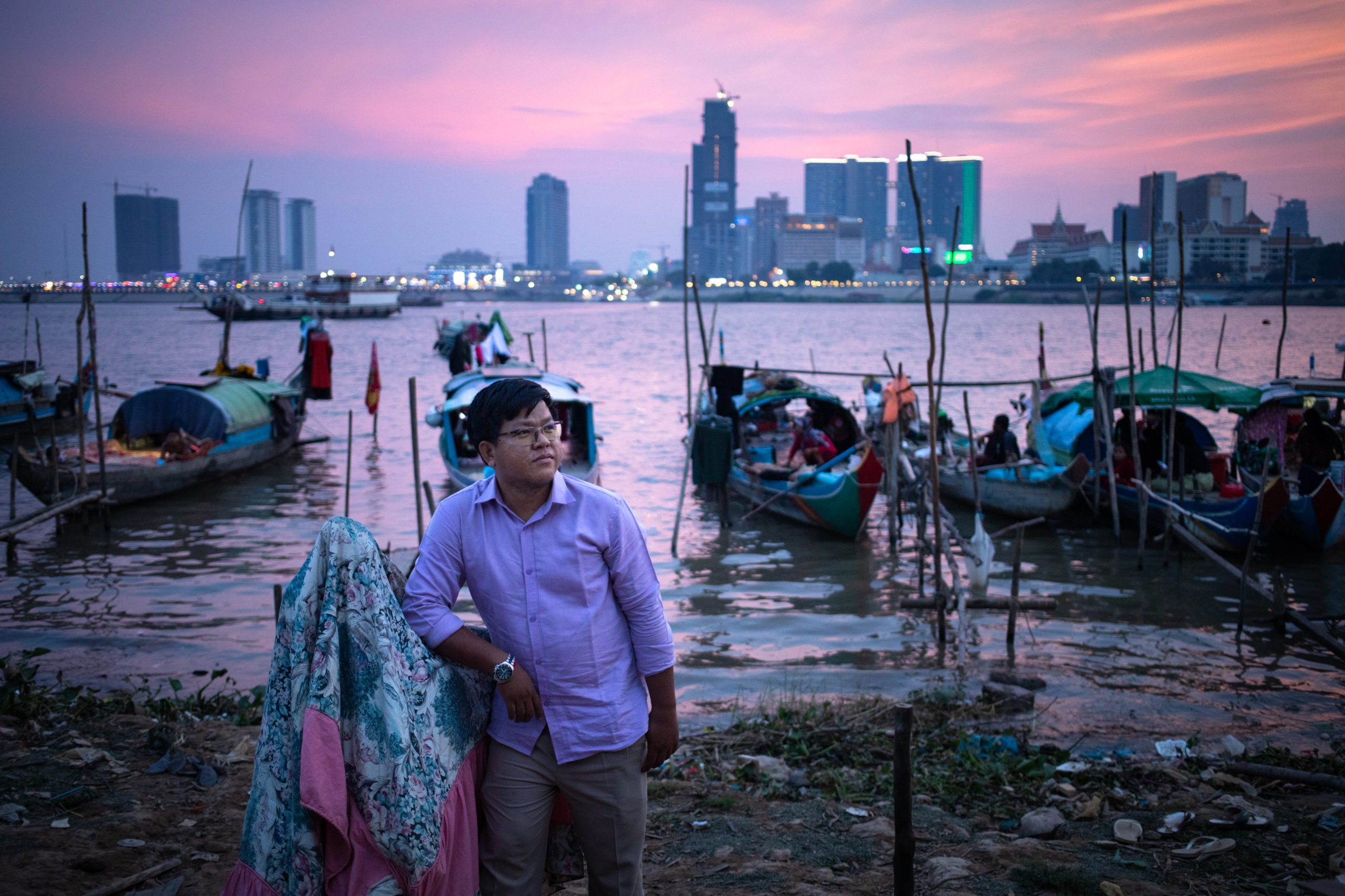 Senglong Youk, Waterkeeper of the Mekong and Tonle Sap poses for a photo in front of a Cham muslim fishing community in Chrouy Changvar, a peninsula between both rivers on the outskirts of Phnom Penh. Phnom Penh, Cambodia. 
